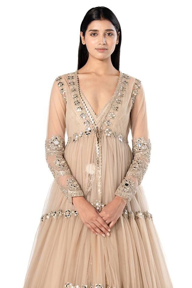 Beige long tiered jacket with mirror embroidery. Comes with sleeveless anarkali with mirror embroidered hem.
Components: 2
Pattern: Embroidered
Type Of Work: Mirror
Neckline: Plunged V
Sleeve Type: Jacket: Long, Anarkali: Sleeveless
Fabric: Anarkali- Organza, Jacket- Net
Color: Beige
Other Details: 
Back tassel tie anarkali
Front tie-up jacket
Occasion: Destination Wedding - Aza Fashions Embellished Anarkali Kurta With Long Sleeves, Bollywood Style Embellished Long Sleeve Bandhgala, Embellished Bollywood Bandhgala With Long Sleeves, Embellished Bollywood Bandhgala, Anarkali Long Sleeve Festive Outerwear, Festive Long Sleeve Embellished Nehru Jacket, Embellished Long Sleeve Kurta For Navratri, Long Sleeve Embellished Kurta For Navratri, Navratri Long Sleeve Embellished Kurta