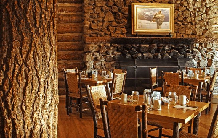 a dining room with tables and chairs in front of a fire place that has a painting on the wall