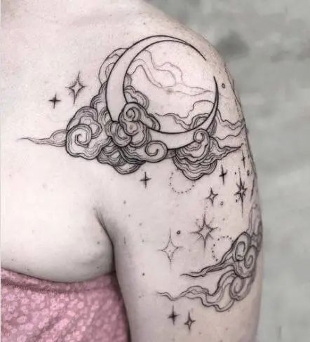 a woman with a tattoo on her shoulder is looking at the moon and clouds in the sky