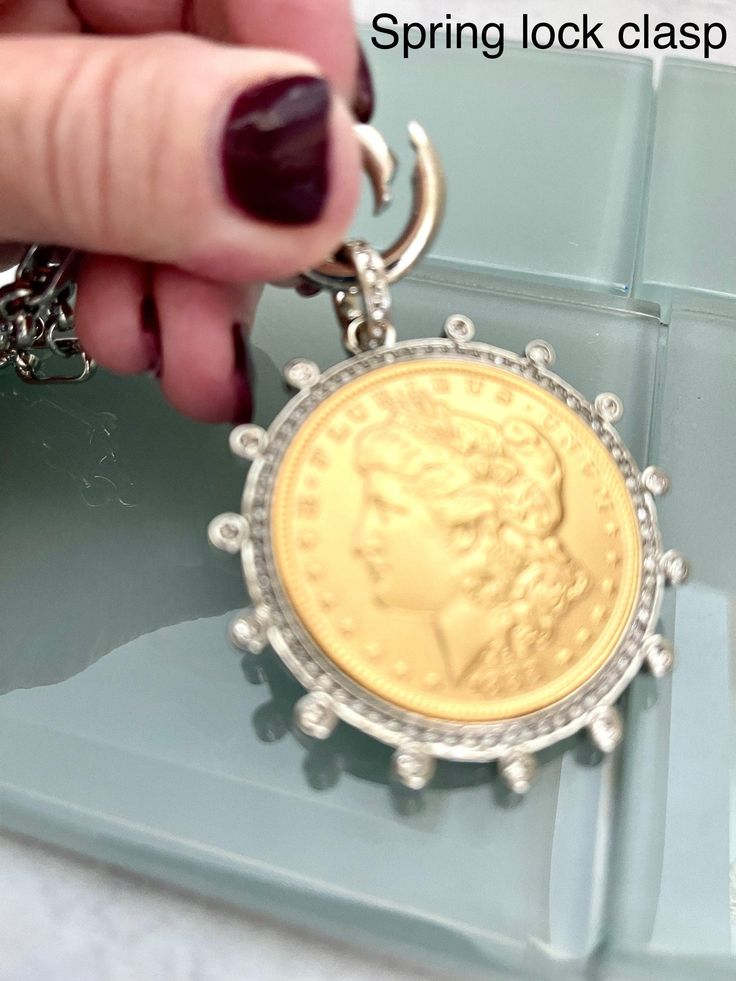 Beautiful reproduction vintage Gold coin pendant, Morgan Peace Dollar coin in a silver bezel with cubic zirconia stones. The bale attached to the coin is also encrusted with CZ stones. The coin is 22k gold plated and elegantly hangs from a multi link Rhodium plated brass chain and a spring lock CZ clasp The spring lock closure not only makes it easy to open and close the necklace for those with difficulty but adds to the creativity of the jewelry piece. Will enhance any outfit. Jeans to the litt Gold Coin Pendant, Silver Coin Necklace, Peace Dollar, Outfit Jeans, Dollar Coin, Gold Coin, Coin Necklace, Keep Jewelry, Coin Pendant