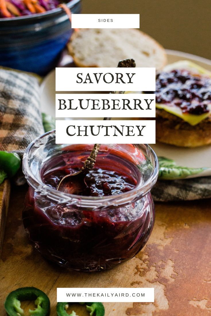 a jar of blueberry chutney sitting on top of a cutting board