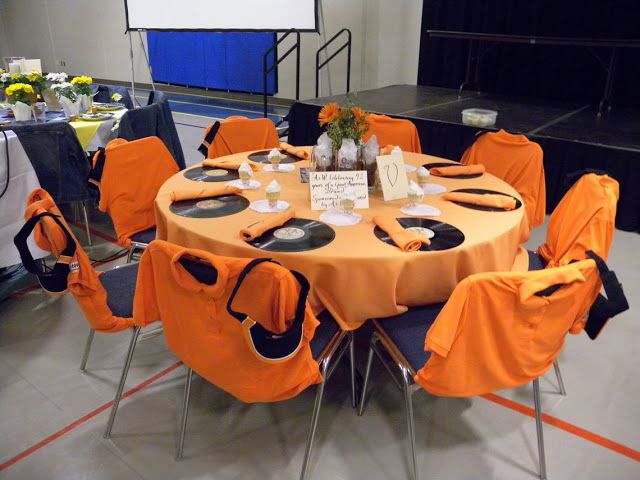 a round table with orange and black cloths on it is set up for an event