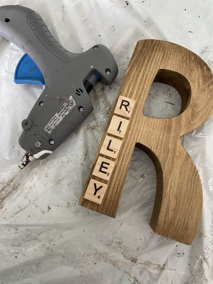 a wooden block with the word riley spelled out in scrabble letters next to a stapler