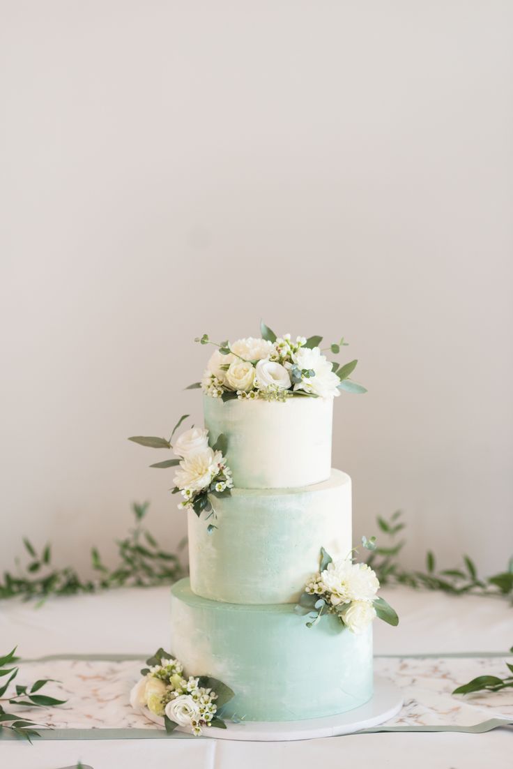 a three tiered cake with white flowers and greenery