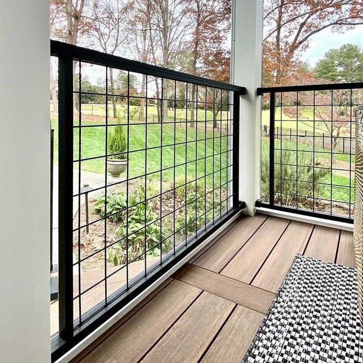 an empty porch with black and white rugs on the wooden floor next to large windows