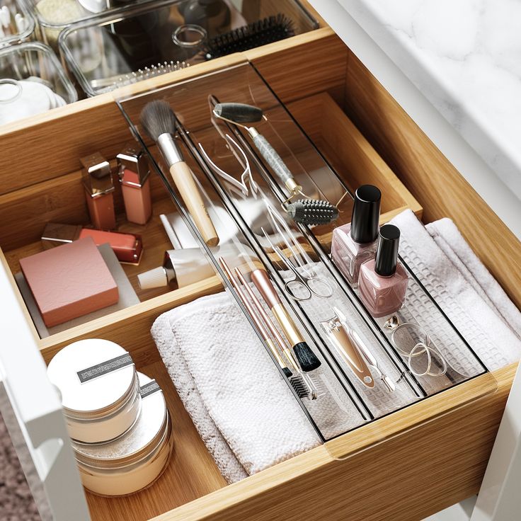 an open drawer filled with cosmetics and other items on top of a counter next to a sink