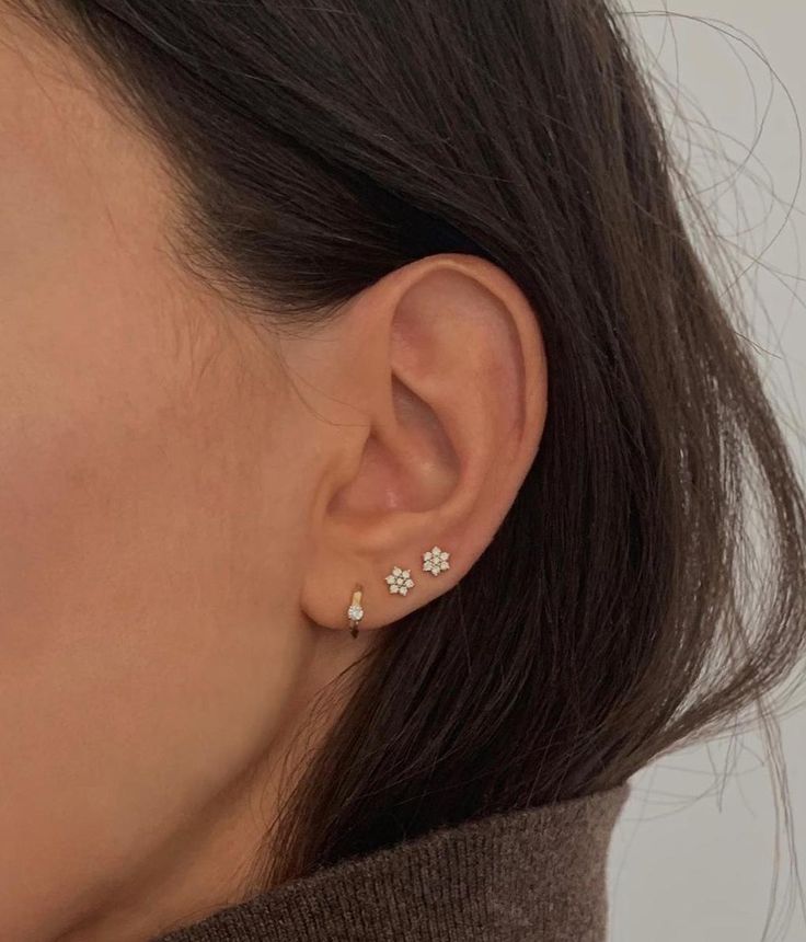 a woman wearing an earring with three small flowers on it