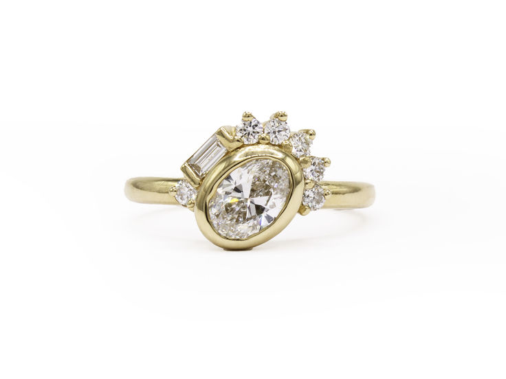 a yellow gold engagement ring with an oval cut diamond and baguettes on the side