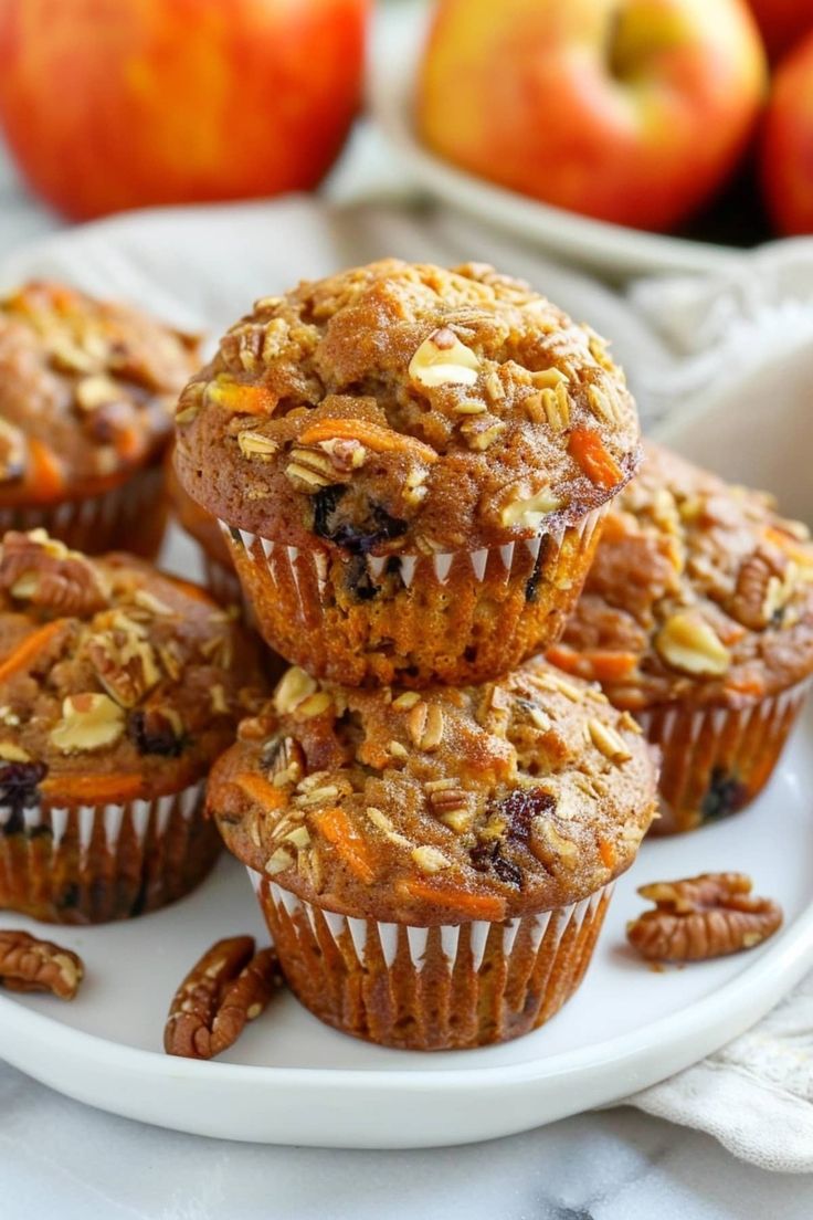 several muffins on a white plate with apples in the backgroung