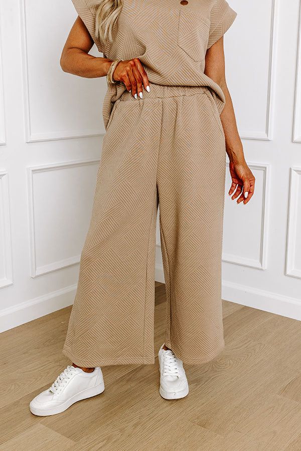 - These casual-chic pants are a must-have! Their stylish design and relaxed fit make it perfect for elevating your everyday wardrobe. Achieve a luxe look with this fabulous piece! - Unlined material with a trendy texture - An elastic waistband - Functional side pockets - A wide legged silhouette that ends in straight hemlines Fall Wide Leg Khaki Pants With Elastic Waistband, Khaki Wide Leg Pants With Elastic Waistband For Fall, Chic Wide-leg Sweatpants For Fall, Beige Wide-leg Sweatpants For Fall, Chic Cream Wide Leg Pants For Loungewear, Comfortable Brown Fall Pants, Beige Pants With Elastic Waistband For Fall, Chic Taupe Bottoms, Casual Taupe Wide Leg Bottoms