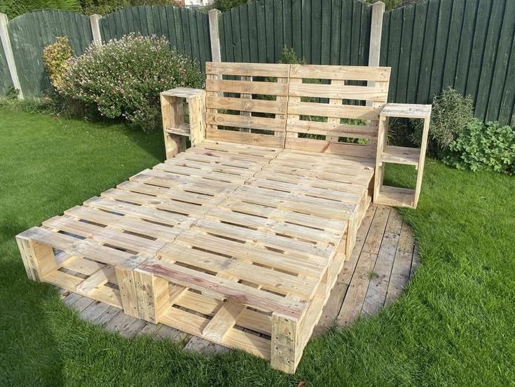 a bed made out of wooden pallets in the grass