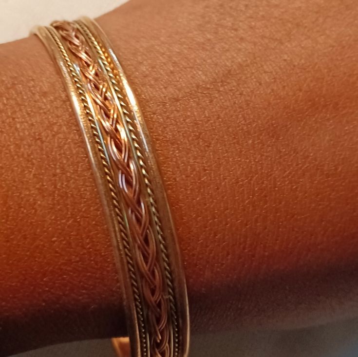 a close up of a person's arm wearing gold bracelets