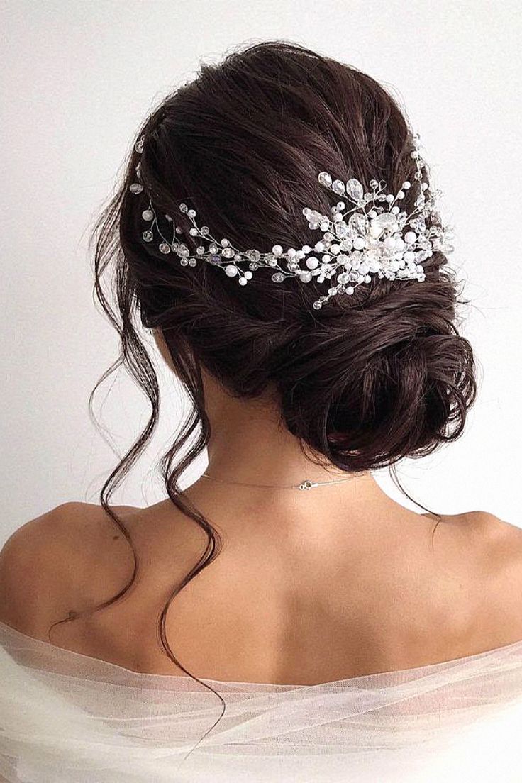 the back of a woman's head wearing a bridal hair comb with pearls on it