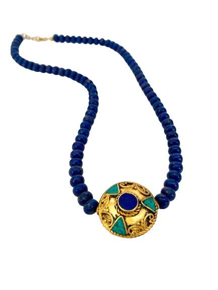 This vibrant lapis necklace is a true statement piece that exudes a sense of natural beauty and elegance. The necklace is beaded with flat lapis beads, each showcasing the unique and mesmerizing patterns of lapis stones. The centerpiece of the necklace is a stunning pendant with lapis and turquoise inlays, set in a brushed gold setting over brass. The combination of lapis and turquoise creates a striking contrast of colors, adding a touch of warmth and vibrancy to the pendant. The brushed gold s Artisan Blue Necklace With Gemstone Beads, Royal Blue Lapis Lazuli Necklaces With Round Beads, Bohemian Blue Lapis Lazuli Beaded Necklace, Royal Blue Lapis Lazuli Necklace With Round Beads, Bohemian Sapphire Round Bead Jewelry, Bohemian Sapphire Beaded Jewelry, Traditional Hand-strung Blue Jewelry, Bohemian Lapis Lazuli Beaded Necklace With Gemstones, Blue Lapis Lazuli Necklace With Large Beads