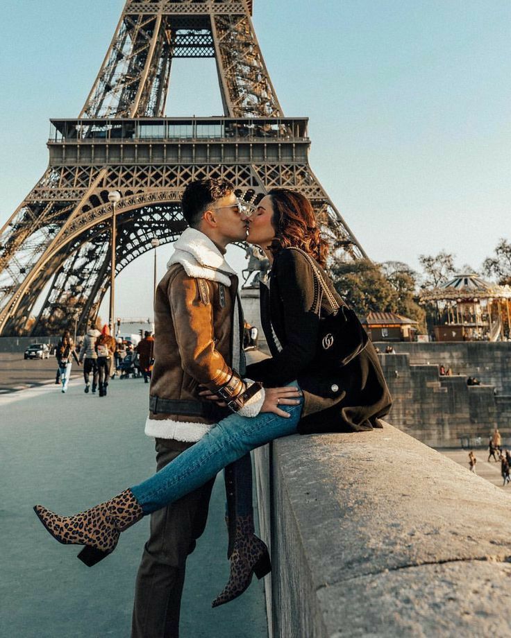 a man and woman kissing in front of the eiffel tower