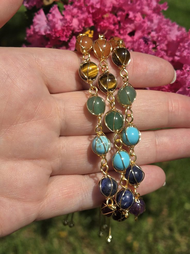 This listing is for ONE chakra crystal bracelet. One will be chosen. Materials are red jasper, carnelian, dyed howlite(blue), green fluorite, lapis lazulie, tiger eye and amethyst.  So pretty and adjustable! Beads are 8mm  All orders are packaged with care, sent with love and gratitude🙏 Bohemian Wire Wrapped Crystal Bracelet With Round Beads, Bohemian Wire-wrapped Crystal Bracelet With Round Beads, Healing Gemstone Beads Bracelet, Bohemian Aventurine Bracelets For Healing, Spiritual Amber Crystal Bracelet With Gemstone, Hand Wrapped Agate Crystal Bracelet Spiritual, Multicolor Tumbled Jewelry For Healing, Spiritual Amber Crystal Gemstone Bracelet, Amber Gemstone Bracelet For Healing