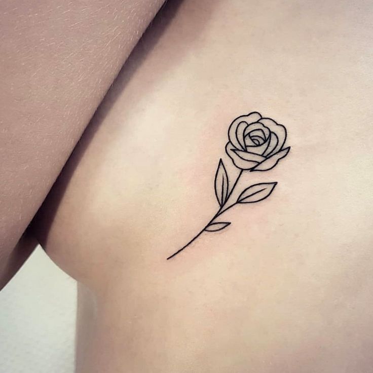 a small rose tattoo on the back of a woman's left shoulder and arm