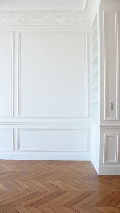 an empty room with white walls and wood flooring in the center, along with wooden parquet floors