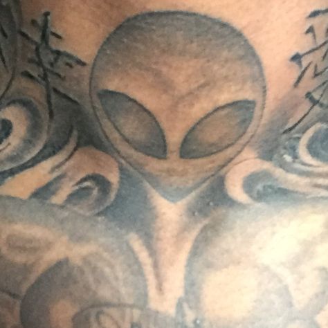 an alien face tattoo on the chest