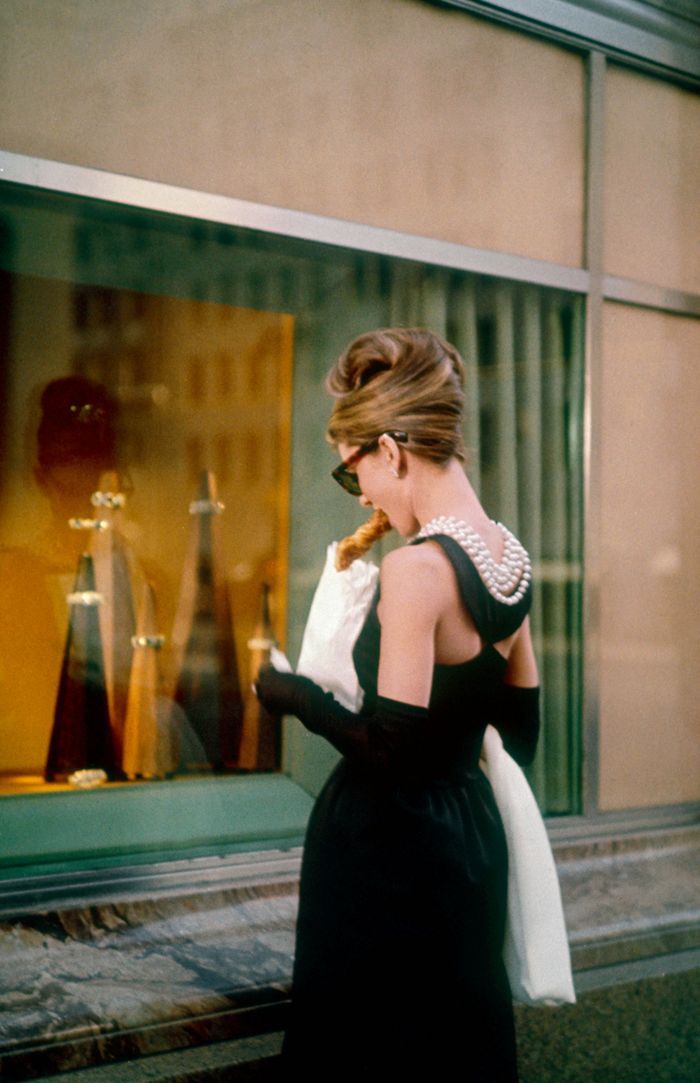 a woman walking down the street in front of a store window