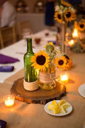 the table is set with sunflowers, candles and mason jars for centerpieces