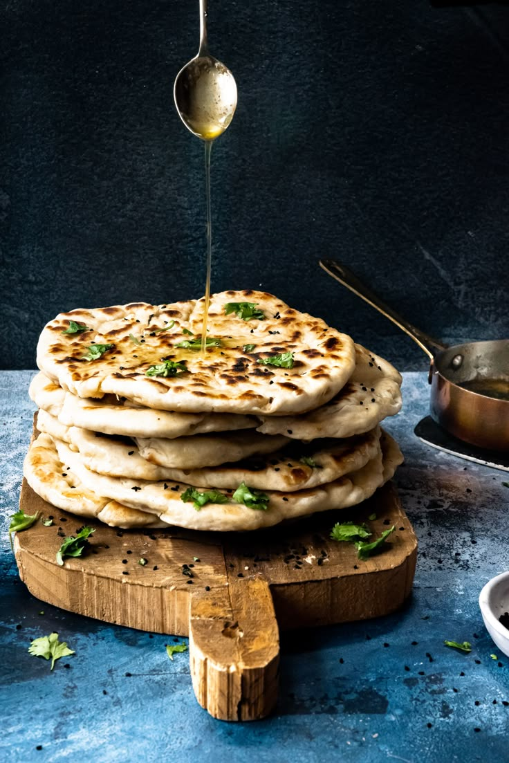 a stack of pita bread being drizzled with olive oil