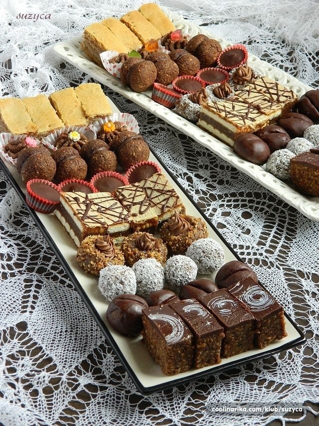 two trays filled with different types of desserts on top of a doily