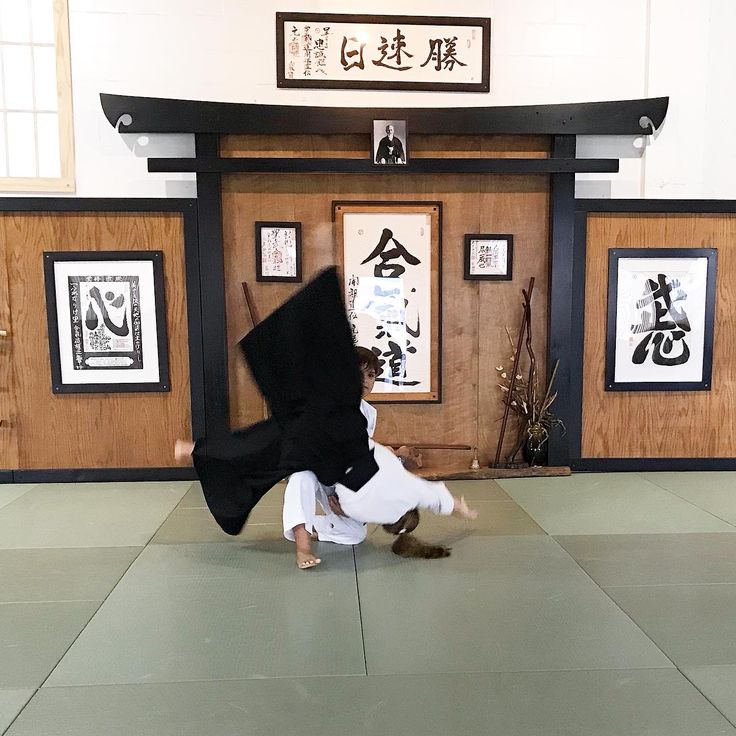 a woman is doing a handstand in front of a wall with pictures on it