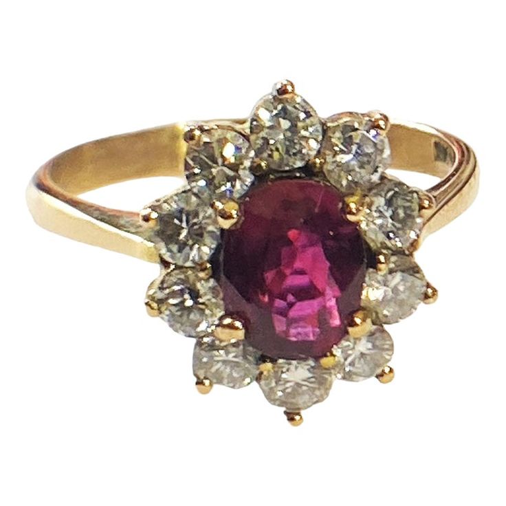 a ring with an oval shaped red stone surrounded by small white and yellow diamond accents