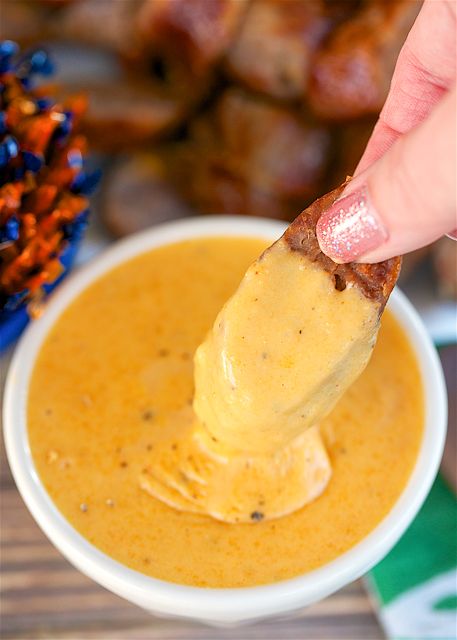 a person dipping something into a small white bowl filled with sauce and other food items