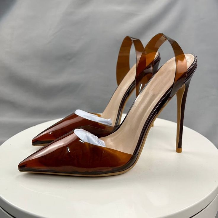 Luxury Evening Heels With Transparent Straps, Elegant Sandals With Transparent Straps And Open Heel, Formal Sandals With Transparent Straps And Open Heel, Luxury Brown Slingback Pumps For Evening, Evening Heels With Transparent Straps And Open Heel, Evening Heels With Transparent Straps, Elegant Evening Sandals With Clear Strap, Elegant Sandals With Transparent Straps And High Heel, Elegant High Heel Sandals With Transparent Straps