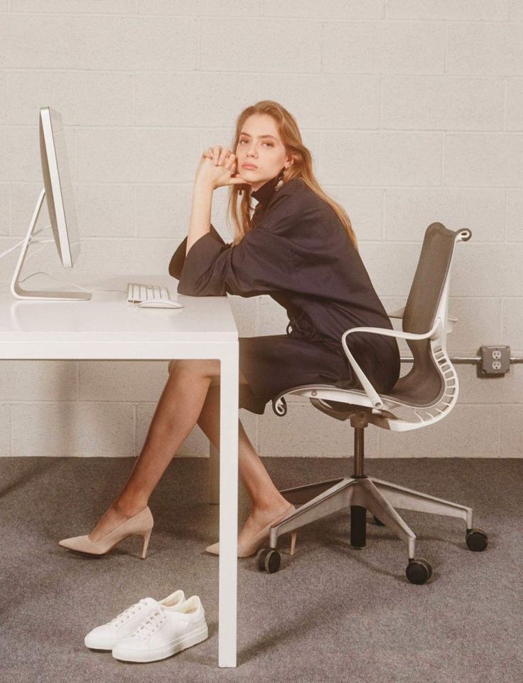 a woman sitting at a desk in front of a computer monitor with her hand on her face