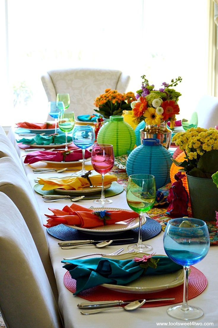 the table is set with colorful dishes and place settings