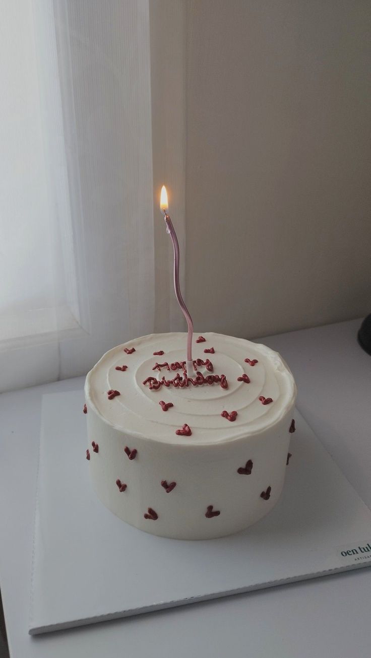 a birthday cake with a single candle on it sitting on top of a white table