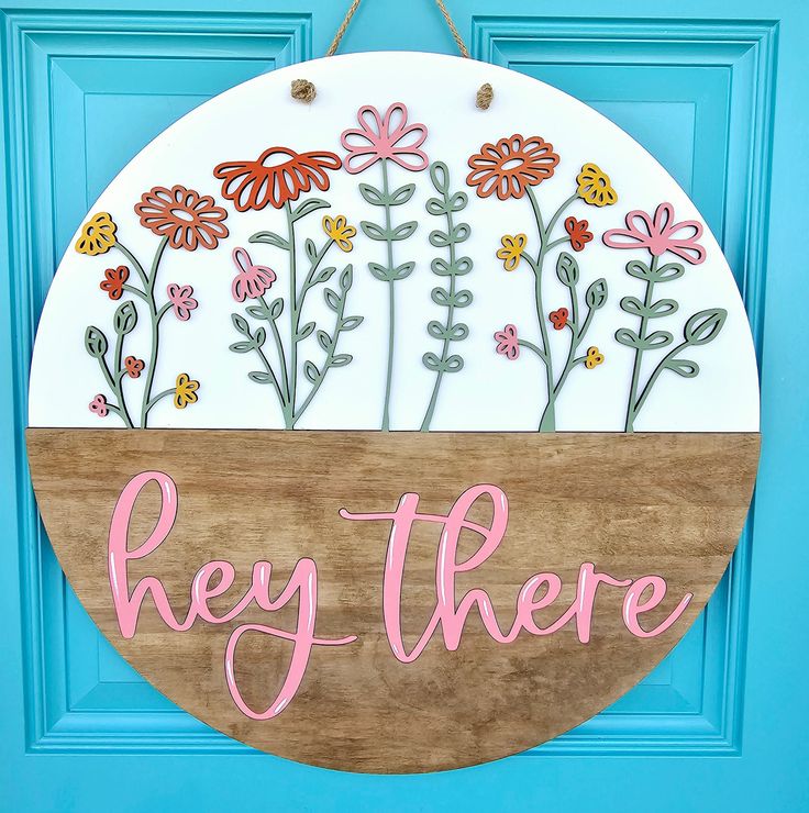 a wooden sign that says hey there with flowers in the center on a blue door