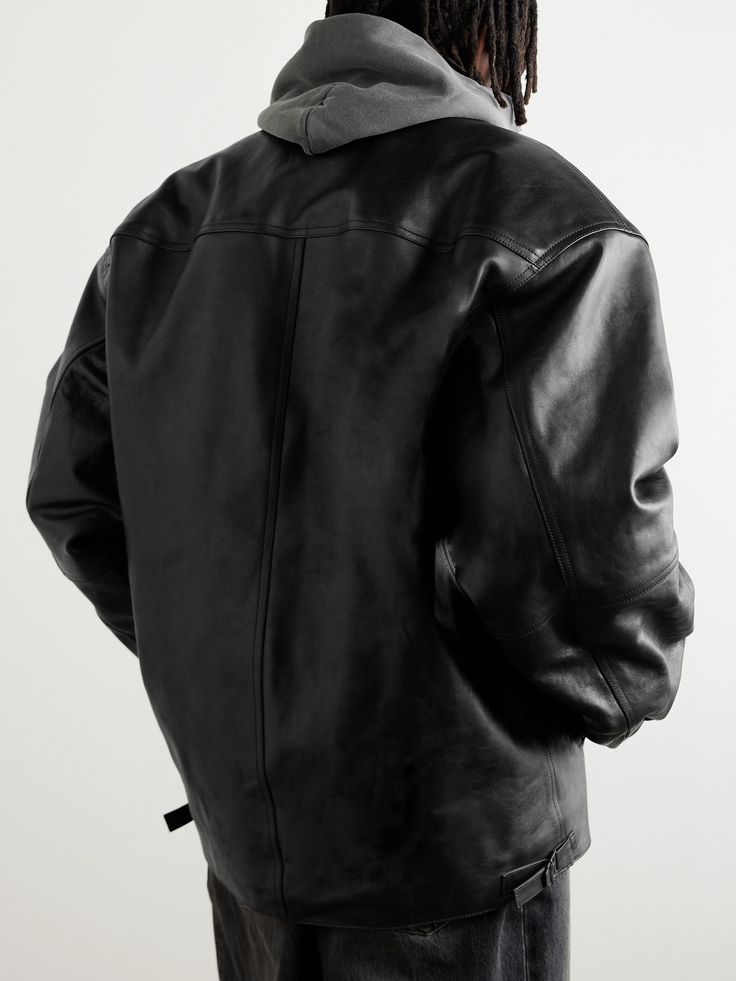 Balenciaga's 'Cocoon Kick' jacket is made from smooth black leather that's crinkled in places for a vintage appearance – the brand has a department dedicated to giving its pieces an aged look. It's lightly padded for both warmth and to enhance its oversized shape. Hooded Leather Jacket For Work, Oversized Leather Biker Outerwear, Classic Oversized Leather Jacket, Black Leather Outerwear With Padded Collar, Oversized Leather Outerwear For Streetwear, Luxury Black Hooded Leather Jacket, Oversized Urban Leather Outerwear, Black Luxury Biker Jacket With Pockets, Luxury Black Biker Jacket With Pockets