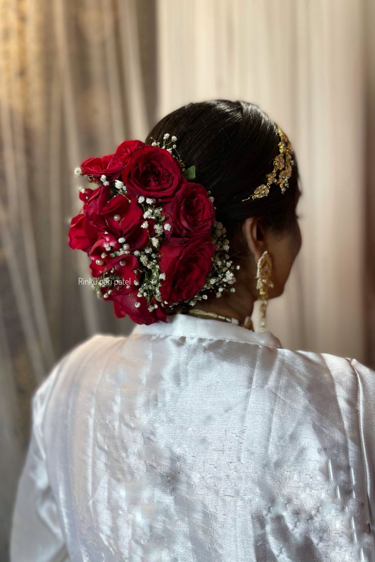 a woman with flowers in her hair is wearing a white blouse and holding a bouquet of red roses