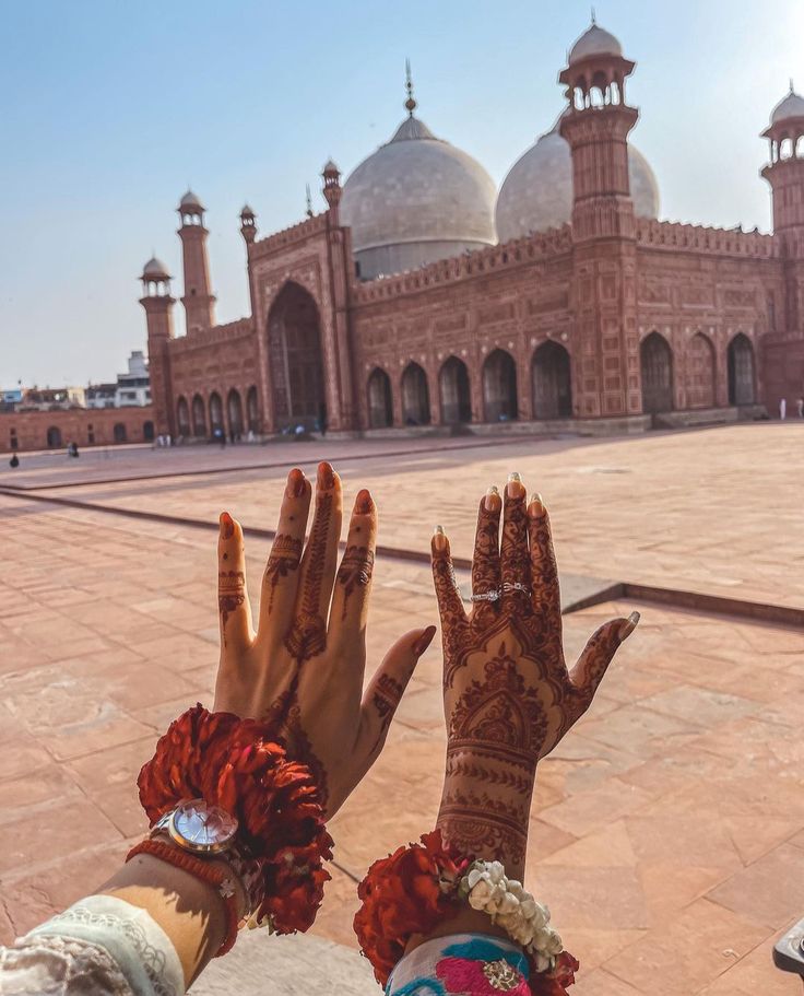 two women with their hands painted in hendi and bracelets are looking at the building