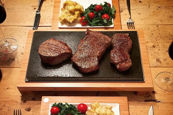 two plates with steak, potatoes and vegetables are on the table next to each other