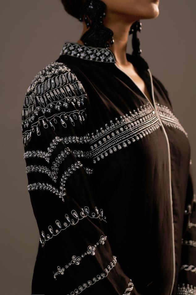 Black full sleeves shirt in summer silk base with sequin flora bloom embroidery, lace embellishments on hem and stand collar neckline. Paired with matching flared palazzo. Components: 2 Pattern: Embroidery Type Of Work: Sequin Neckline: Stand Collar Sleeve Type: Full Fabric: Summer Silk Color: Black Other Details:  Attached inner lining Length: Kurta: 28inches Palazzo: 38inches Occasion: Sangeet, Mehendi and Haldi - Aza Fashions Bloom Embroidery, Lace Embellishments, Flared Palazzo, Pant Sets, Pattern Embroidery, Embroidery Lace, Silk Embroidery, Work Shirt, Full Sleeves