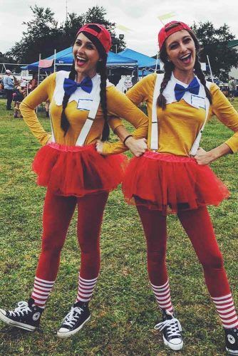 two women dressed in costumes standing next to each other on the grass at an outdoor event