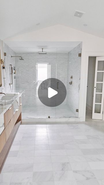 a large bathroom with marble floors and white tile on the walls, along with a walk in shower