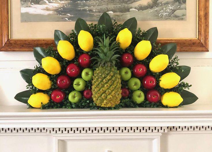 a pineapple surrounded by apples, oranges and lemons in front of a painting