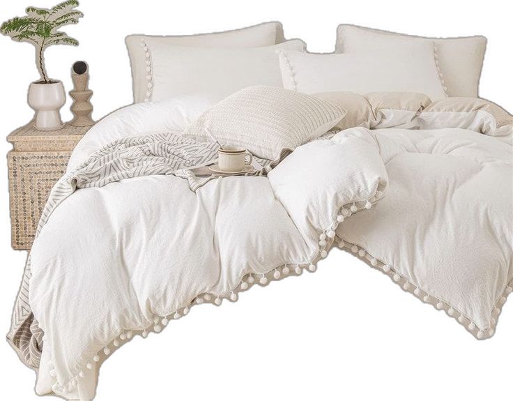 a bed with white linens and pillows on top of it next to a wicker table