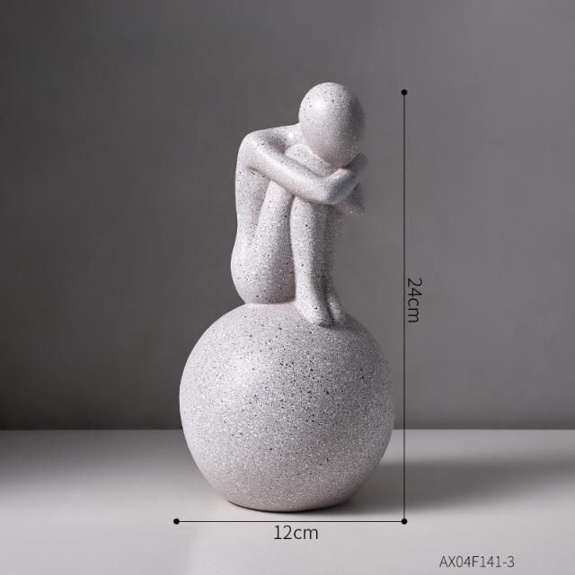 a white statue sitting on top of a ball next to a gray wall with measurements