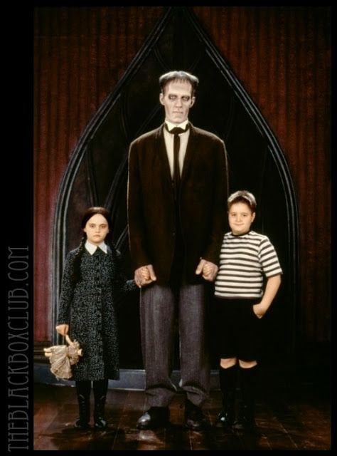 two children and an adult standing in front of a giant fake man wearing a suit