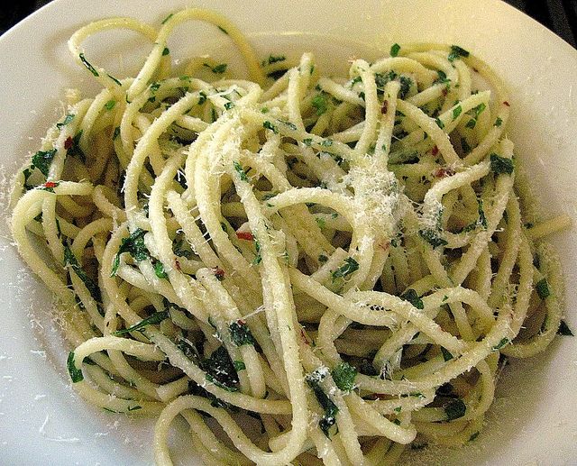 pasta with pesto and parmesan cheese in a white bowl on a stove