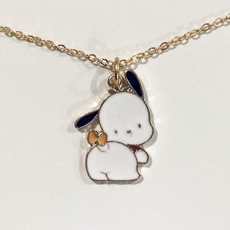 a necklace with a small white dog on it's back and a blue ribbon around its neck