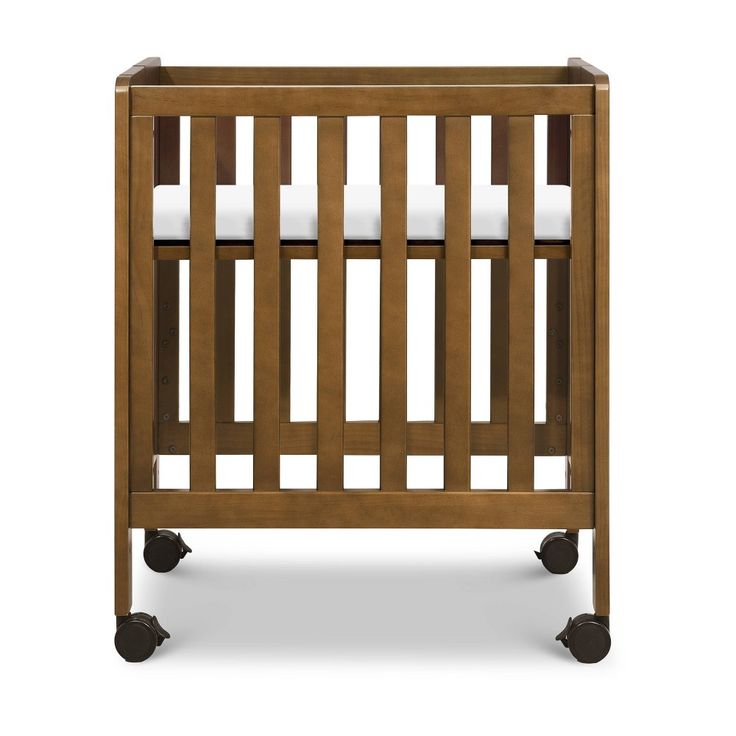 a wooden crib with white sheets on the top and bottom bars, sitting against a white background