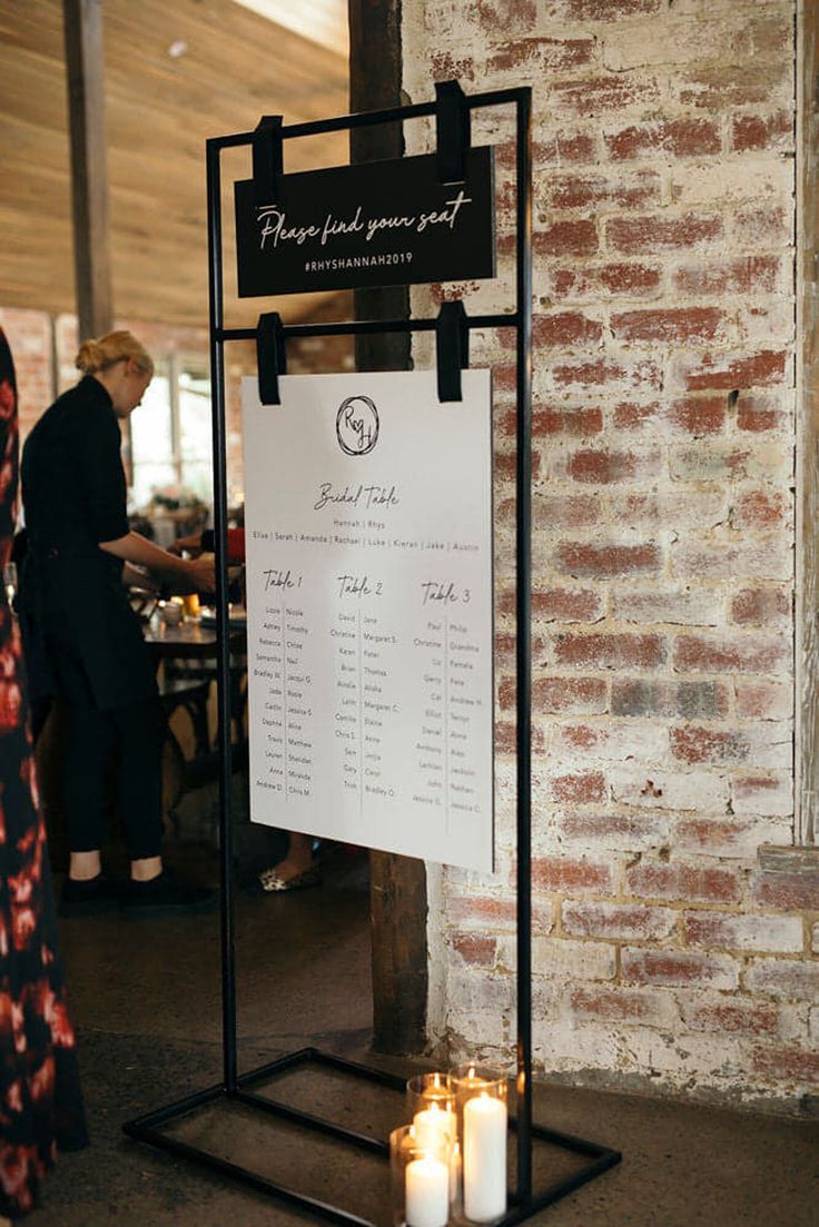 two candles are lit in front of a menu on a stand with a brick wall behind it